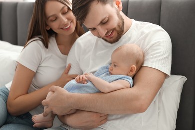 Photo of Happy family. Parents with their cute baby on bed indoors