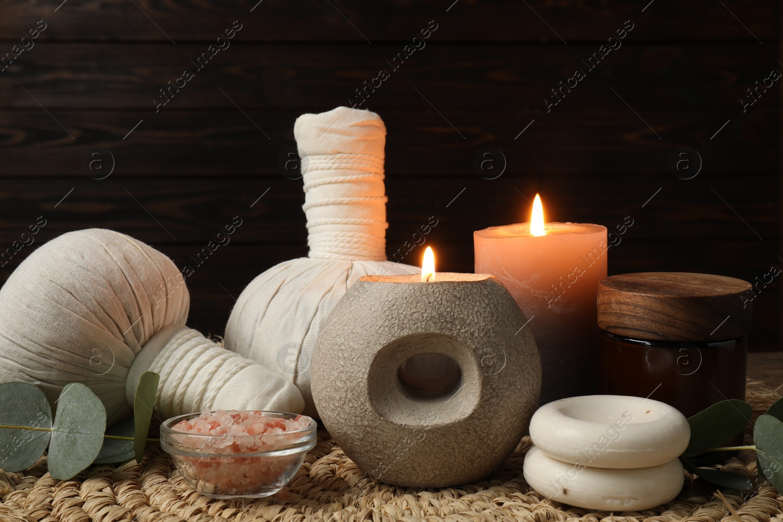 Photo of Aromatherapy. Scented candles, eucalyptus branches and spa products on wicker mat, closeup