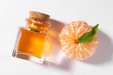 Photo of Aromatic tangerine essential oil in bottle and citrus fruit on white table, top view