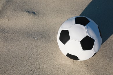 Soccer ball on sand, above view with space for text. Football equipment