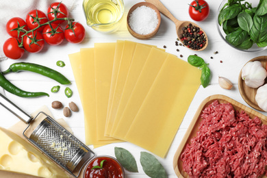 Fresh ingredients for lasagna on white wooden table, flat lay