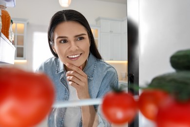Thoughtful woman near refrigerator in kitchen, view from inside