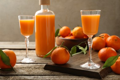 Photo of Delicious tangerine liqueur and fresh fruits on wooden table