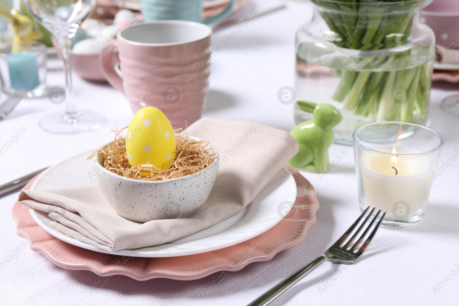 Photo of Festive table setting with painted egg in decorative nest. Easter celebration