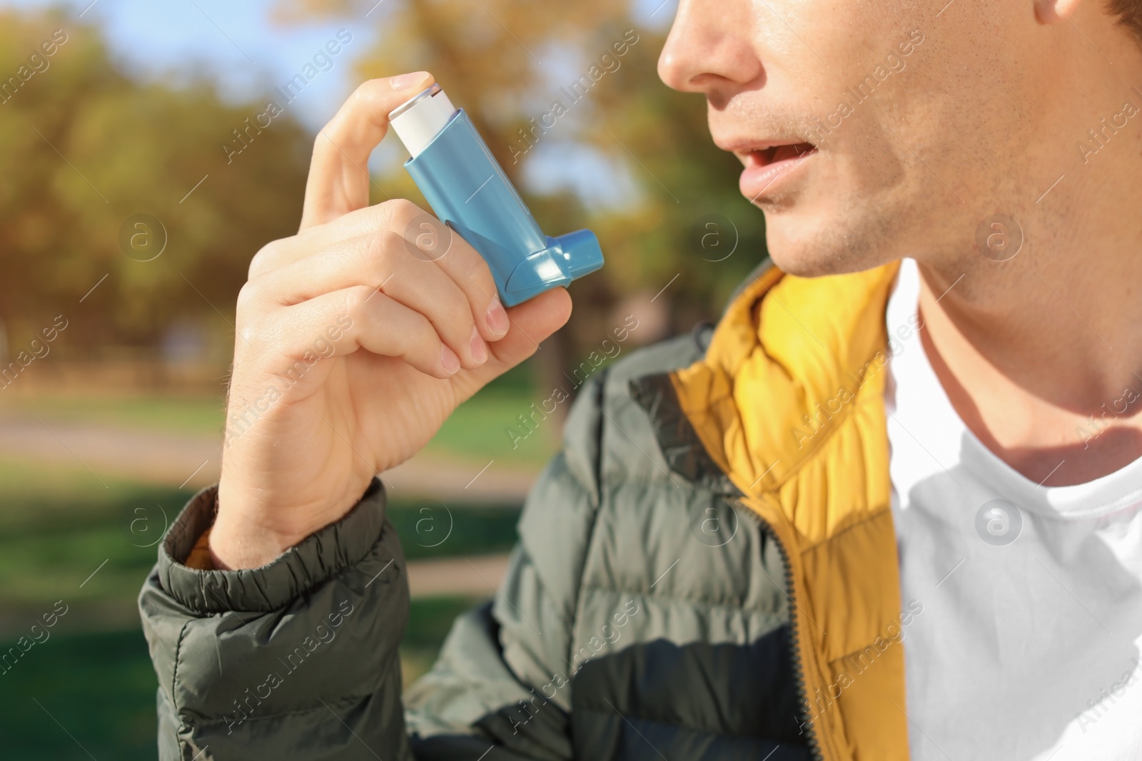 Photo of Man using asthma inhaler outdoors. Health care