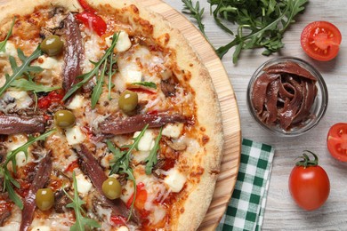 Photo of Tasty pizza with anchovies and ingredients on grey wooden table, flat lay