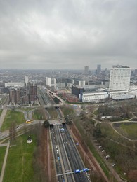 Picturesque view of city with modern buildings and highway on cloudy day