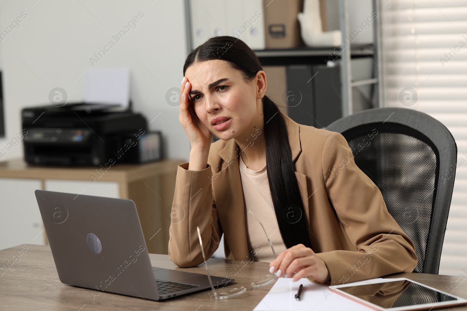 Photo of Woman suffering from headache at workplace in office