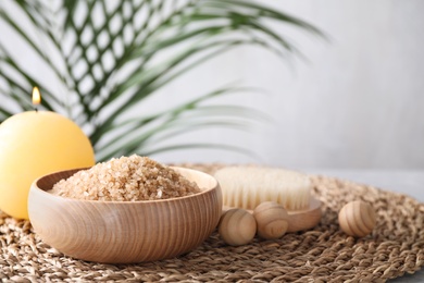 Salt for spa scrubbing procedure and wooden balls on table against grey background