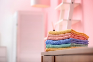 Photo of Clean towels on wooden cabinet against blurred background