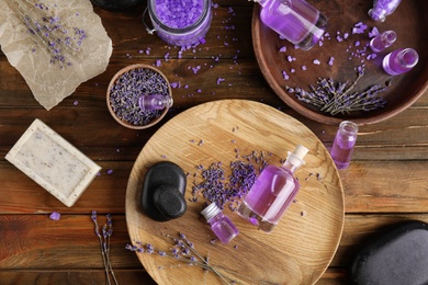 Photo of Flat lay composition with natural herbal oil, soap and lavender flowers on wooden background