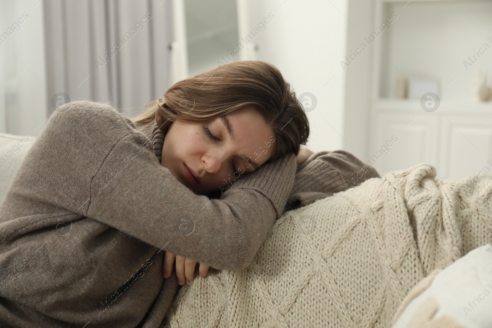 Photo of Sad young woman lying on sofa at home