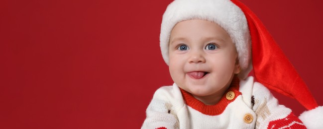 Cute baby wearing Santa hat on red background, banner design with space for text. Christmas celebration