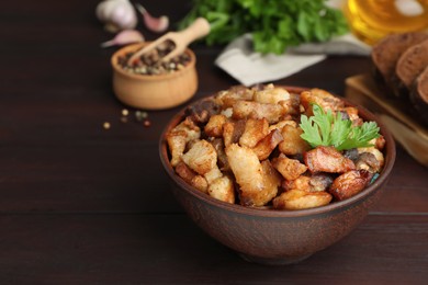 Tasty fried cracklings on wooden table, space for text. Cooked pork lard