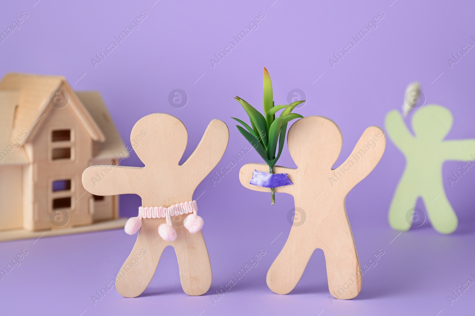 Photo of Wooden human figures fighting for attention of their beloved on lilac background. Jealousy concept