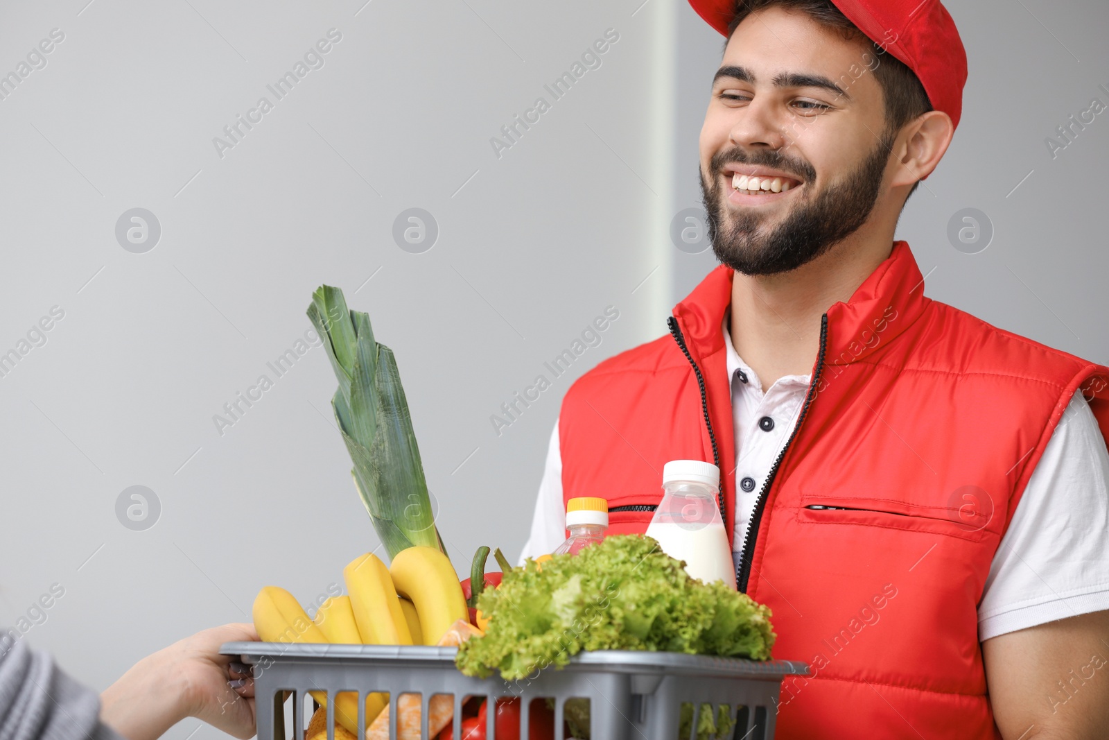 Photo of Young man delivering food to customer indoors