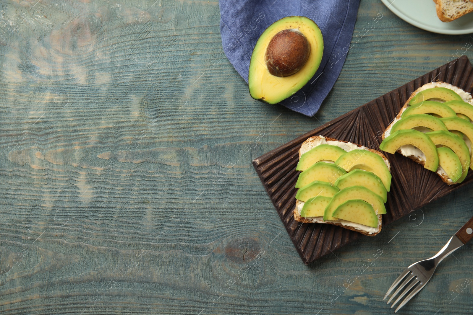 Photo of Flat lay composition with avocado toasts on blue wooden table. Space for text