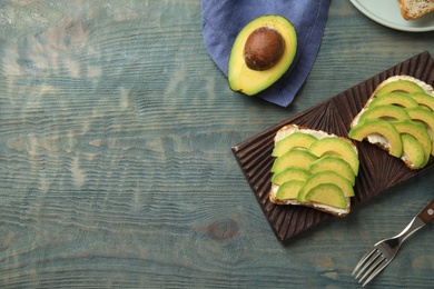 Flat lay composition with avocado toasts on blue wooden table. Space for text