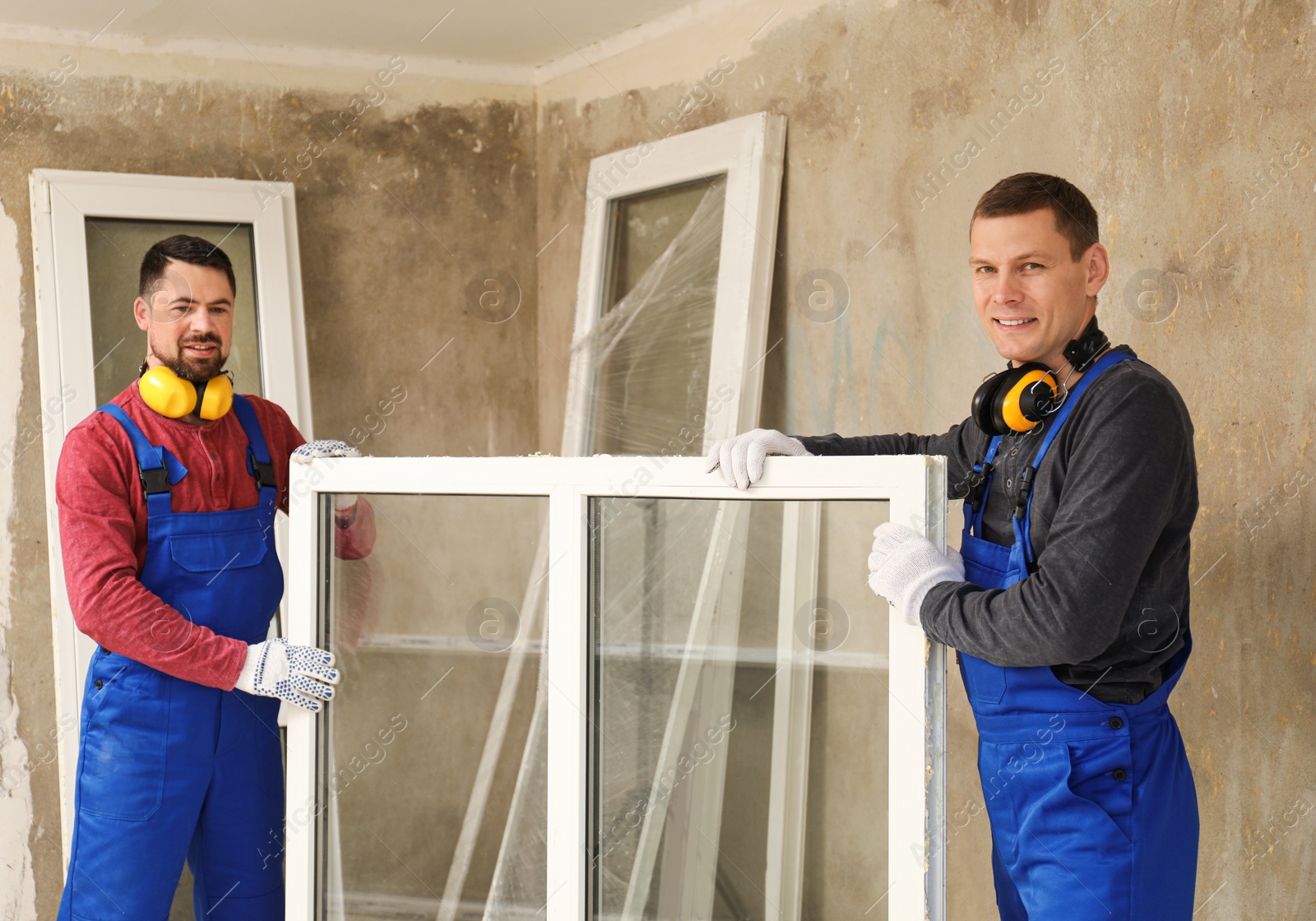 Photo of Workers in uniform with new plastic window indoors