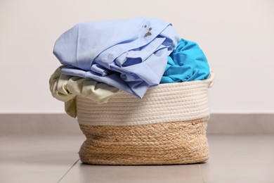 Photo of Laundry basket with clothes near white wall