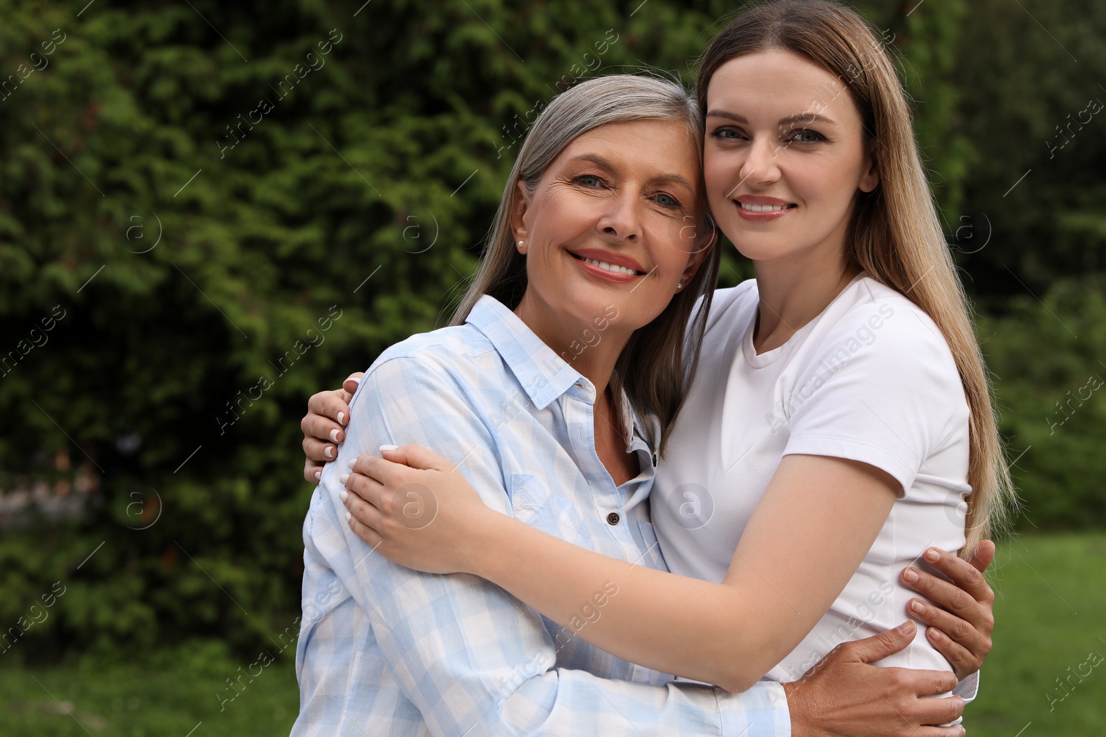 Photo of Happy mature mother and her daughter hugging in park