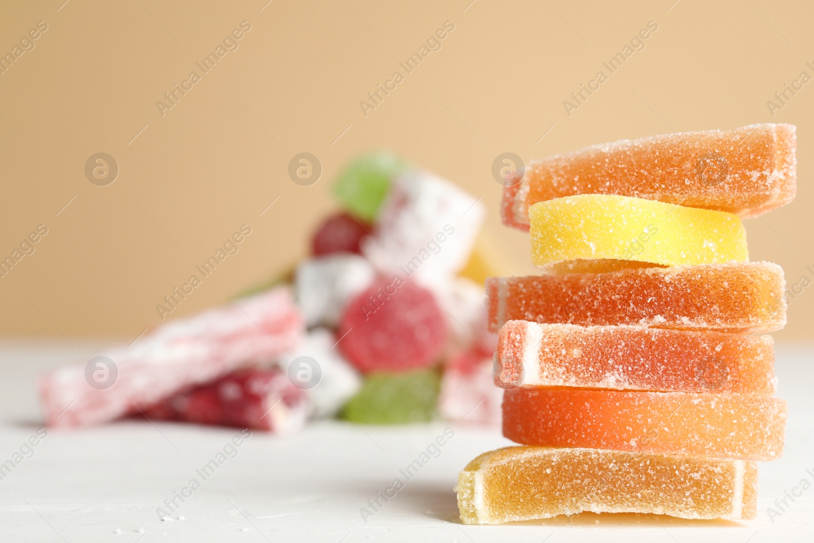 Photo of Pile of delicious bright jelly candies on white table. Space for text