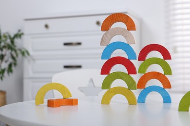 Photo of Colorful wooden pieces of educational toy on white table in room. Motor skills development