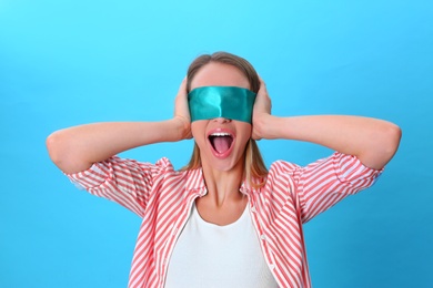 Young woman wearing blindfold on blue background