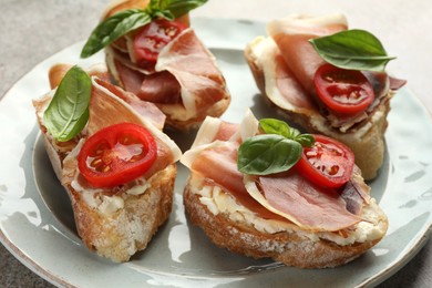 Photo of Tasty sandwiches with cured ham, basil and tomatoes on plate, closeup