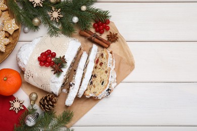 Traditional Christmas Stollen with icing sugar on white wooden table, flat lay. Space for text