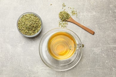 Photo of Aromatic fennel tea and seeds on light grey table, flat lay