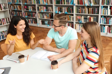 Young people discussing group project at table in library