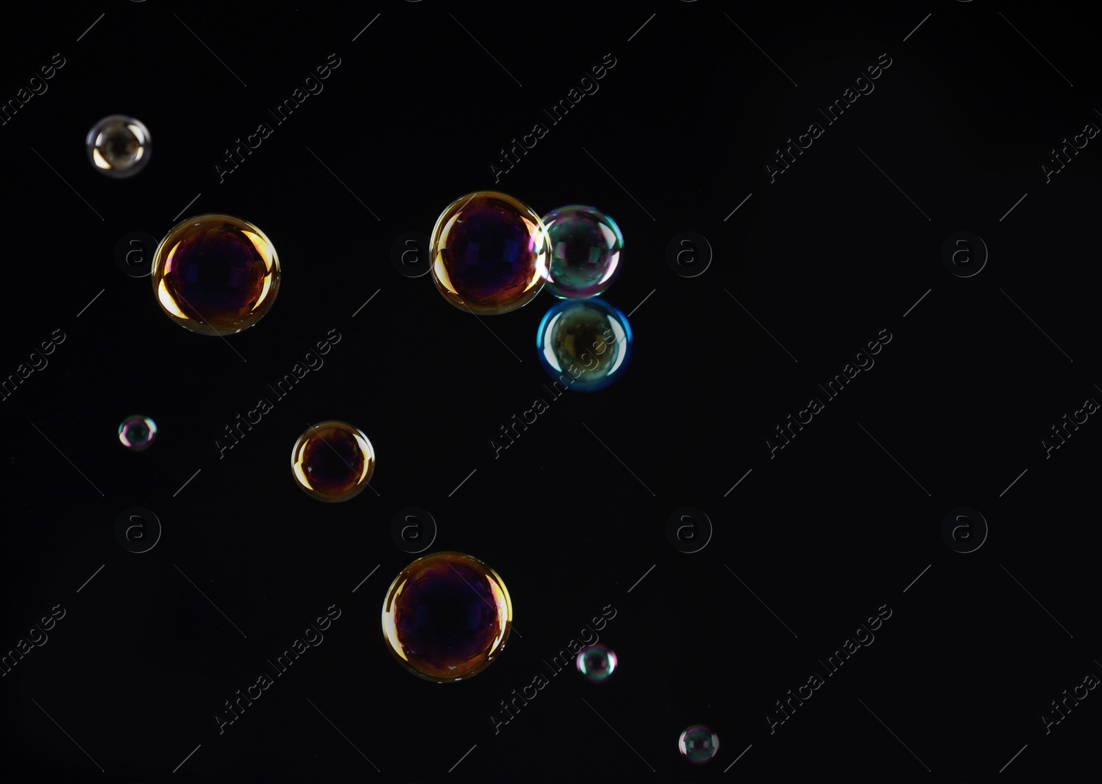 Photo of Beautiful translucent soap bubbles on dark background