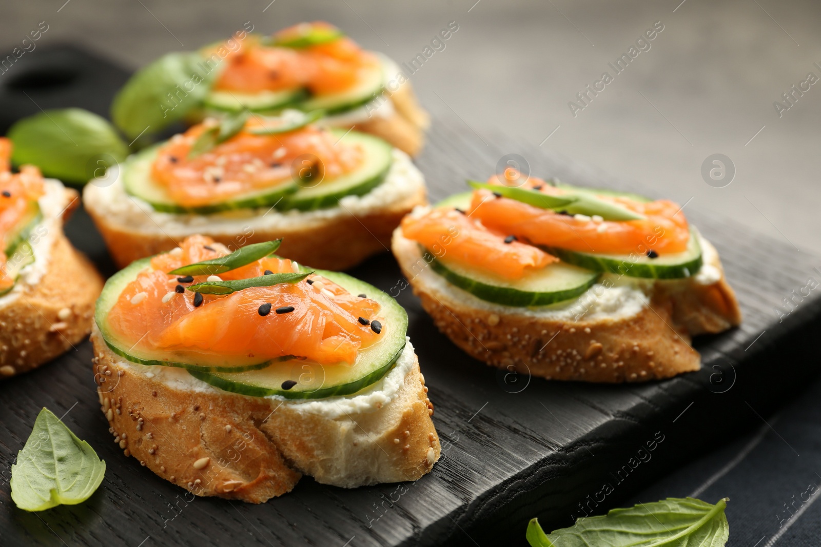 Photo of Tasty canapes with salmon, cucumber and cream cheese on table, closeup