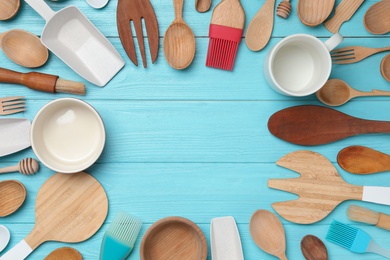 Frame made with modern cooking utensils on light blue wooden table, flat lay. Space for text