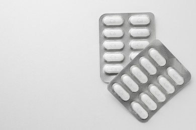 Photo of Calcium supplement pills in blister packs on white background, flat lay. Space for text