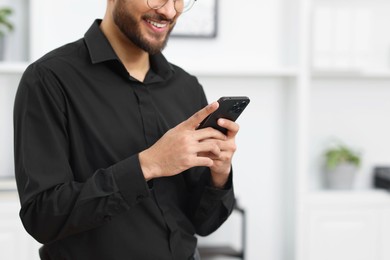 Photo of Man using smartphone in office, closeup. Space for text