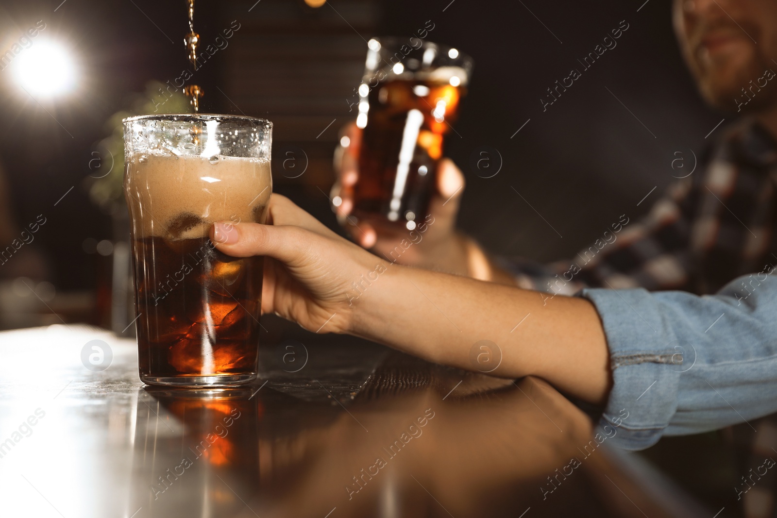 Photo of People with cola in glasses at bar counter indoors, closeup. Pouring beverage