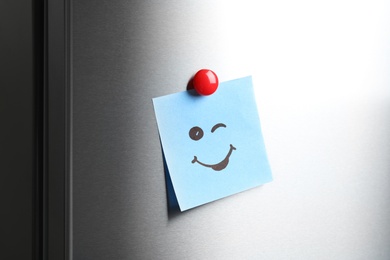 Photo of Note with funny face on refrigerator door