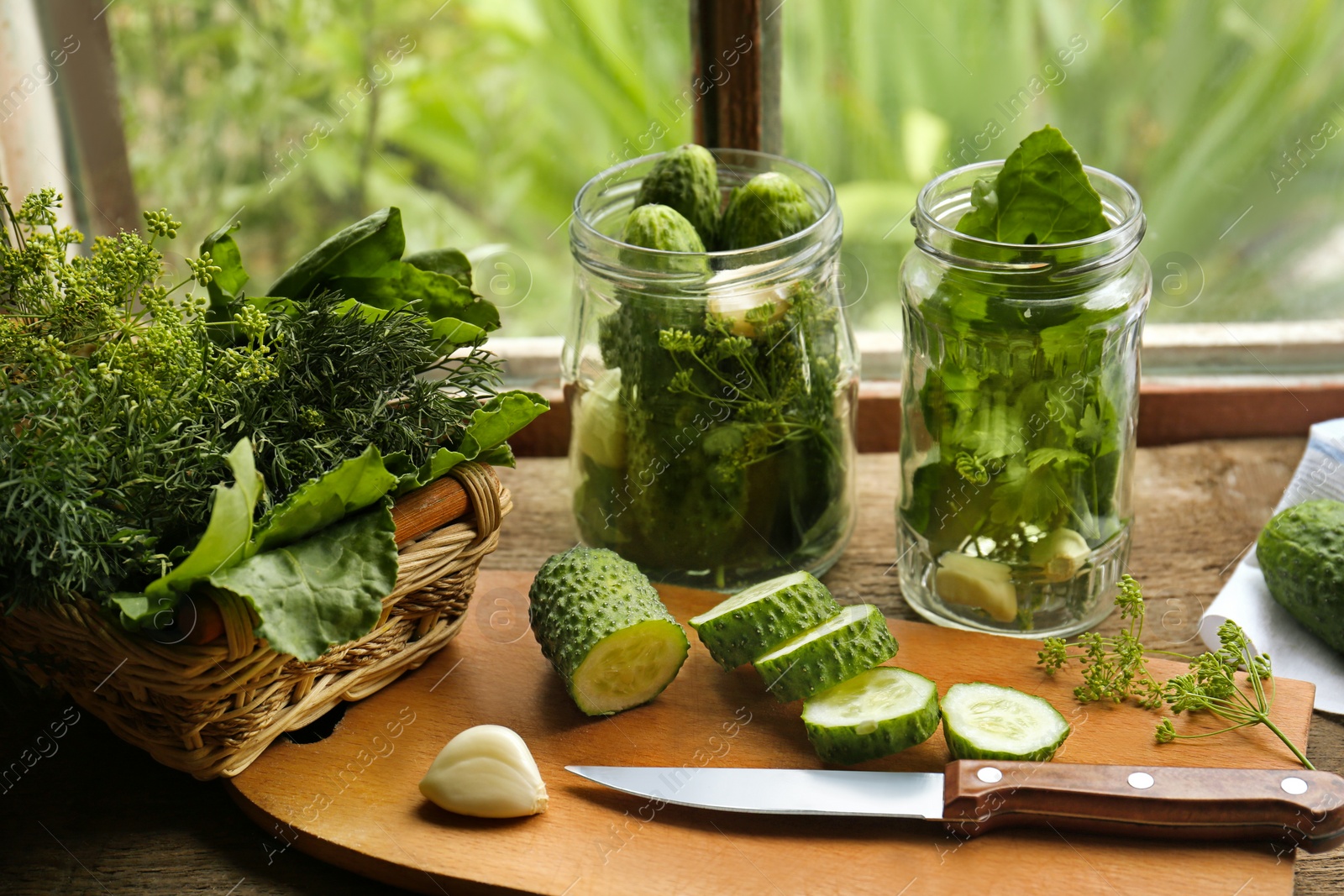 Photo of Glass jars, fresh vegetables and herbs on wooden table indoors. Pickling recipe