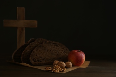 Bread, apple, walnuts and cross on wooden table, space for text. Great Lent season