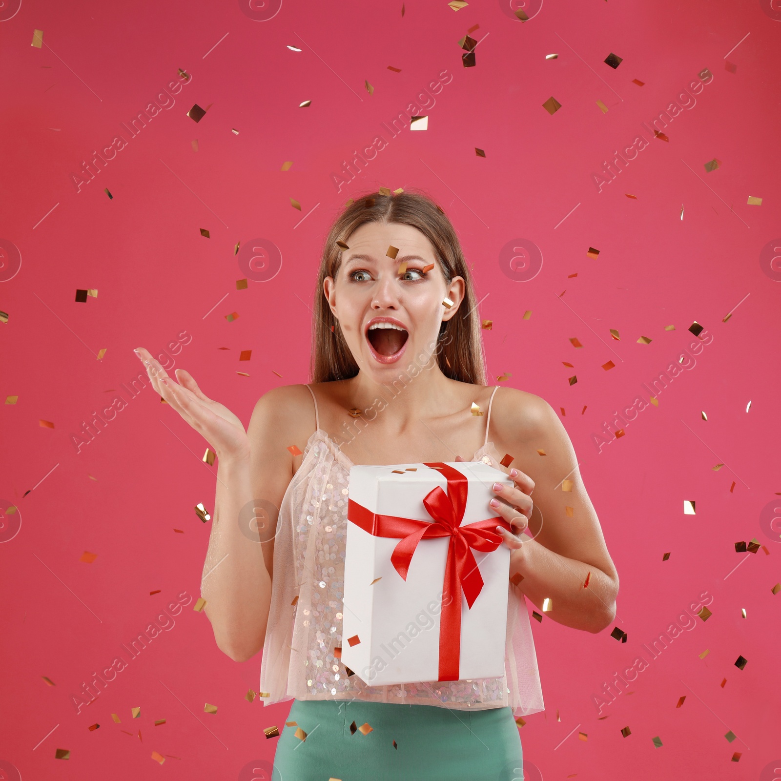 Photo of Emotional young woman with Christmas gift on pink background