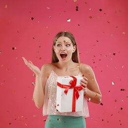 Photo of Emotional young woman with Christmas gift on pink background