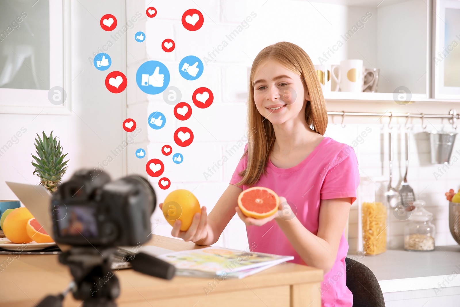 Image of Cute teenage blogger with fruits recording video at table