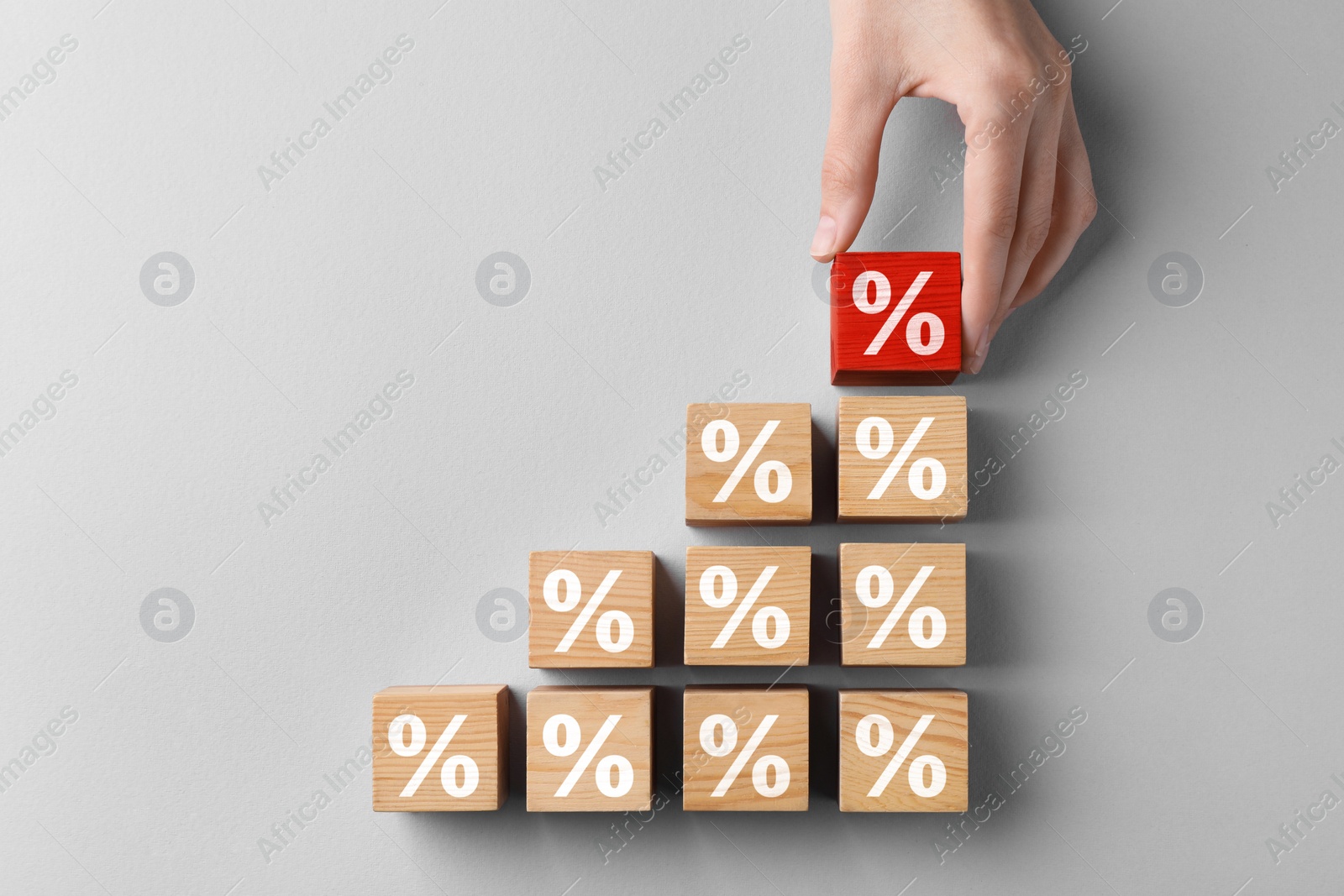 Image of Best mortgage interest rate. Woman putting red cube with percent sign to others on light background, top view