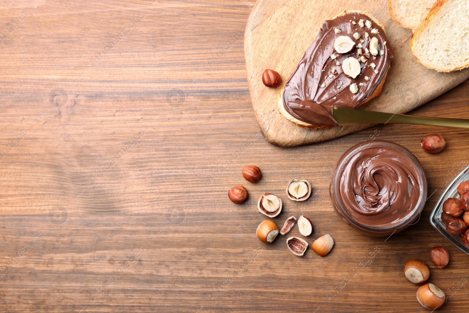Photo of Flat lay composition with tasty chocolate hazelnut spread on wooden table, space for text