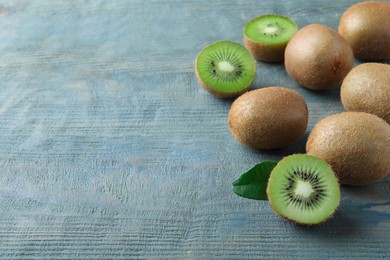 Photo of Fresh ripe kiwis on light blue wooden table, space for text