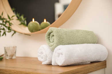 Photo of Fresh towels on wooden table in bathroom