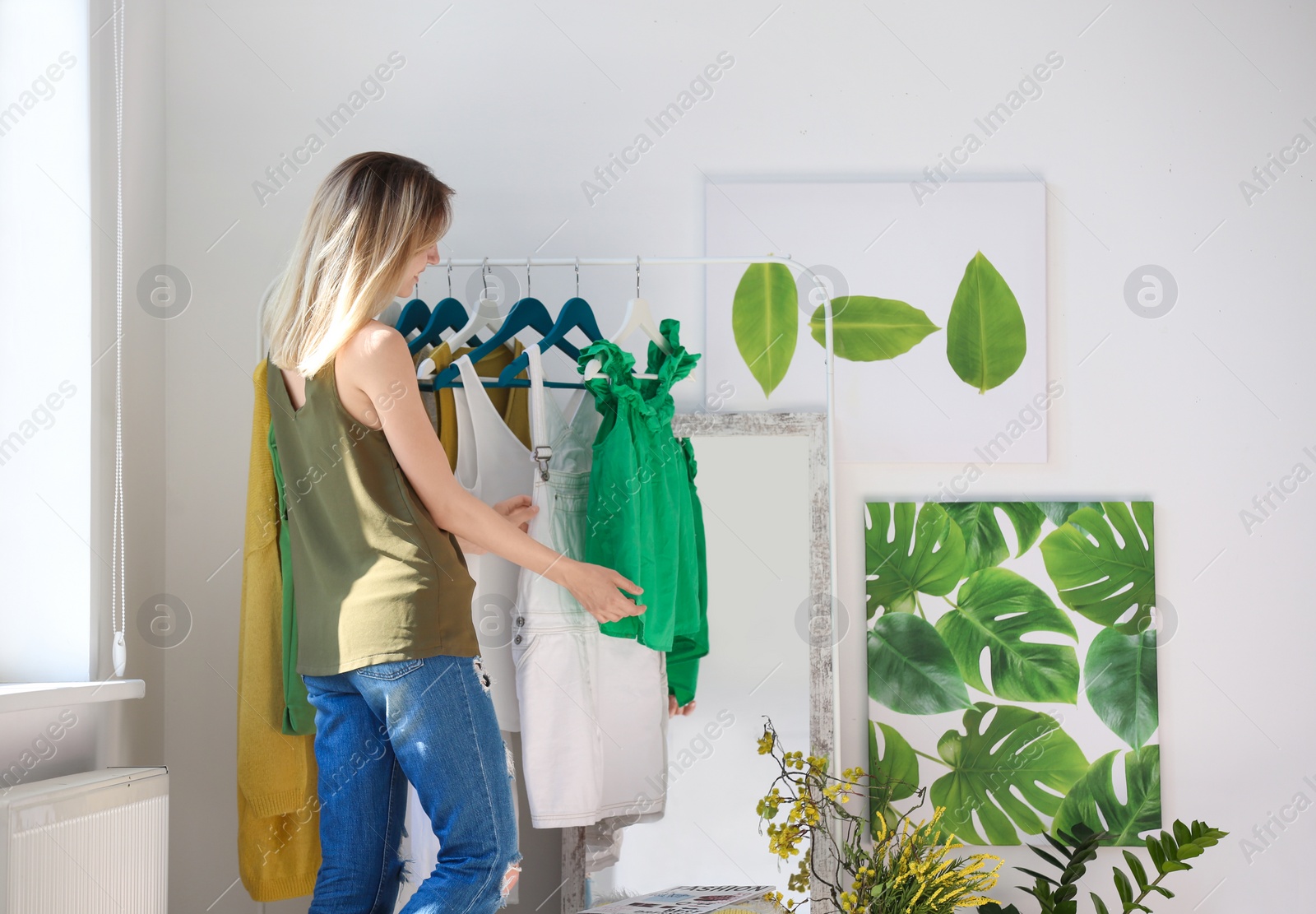 Photo of Young woman near clothes rack indoors. Stylish dressing room interior