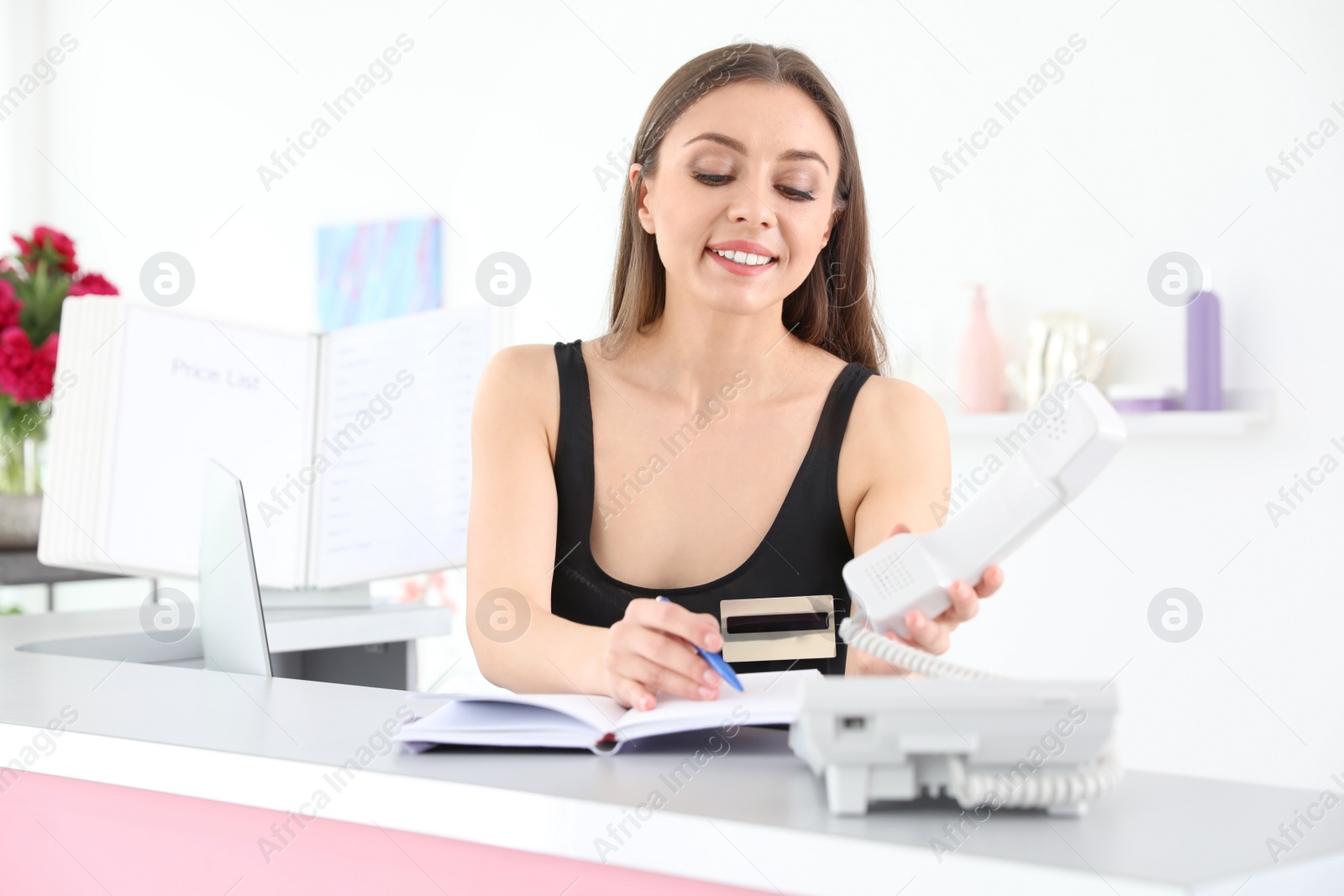Photo of Young receptionist working at desk in beauty salon